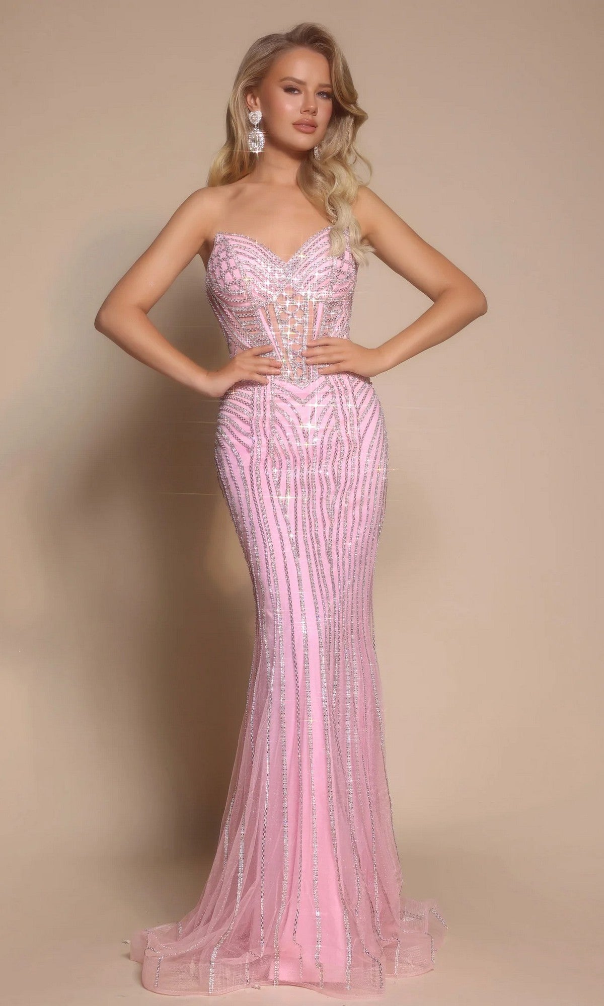 A woman poses against a beige background wearing the Portia and Scarlett PS26156 long formal dress in Silver/Pink, featuring a strapless sweetheart neckline, form-fitting silhouette, silver sequin details, and a sheer corset bodice.